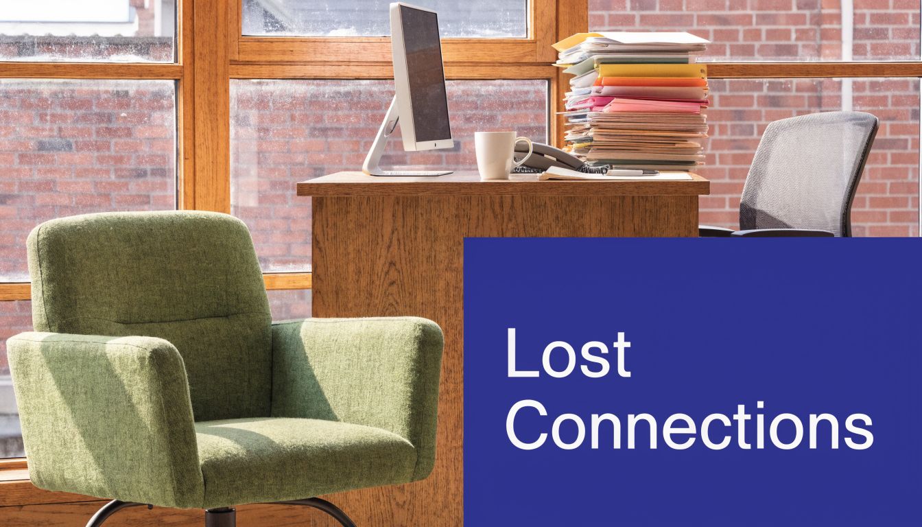 A minimalist office setting with a desk, computer, papers, and green armchair next to blue branding.