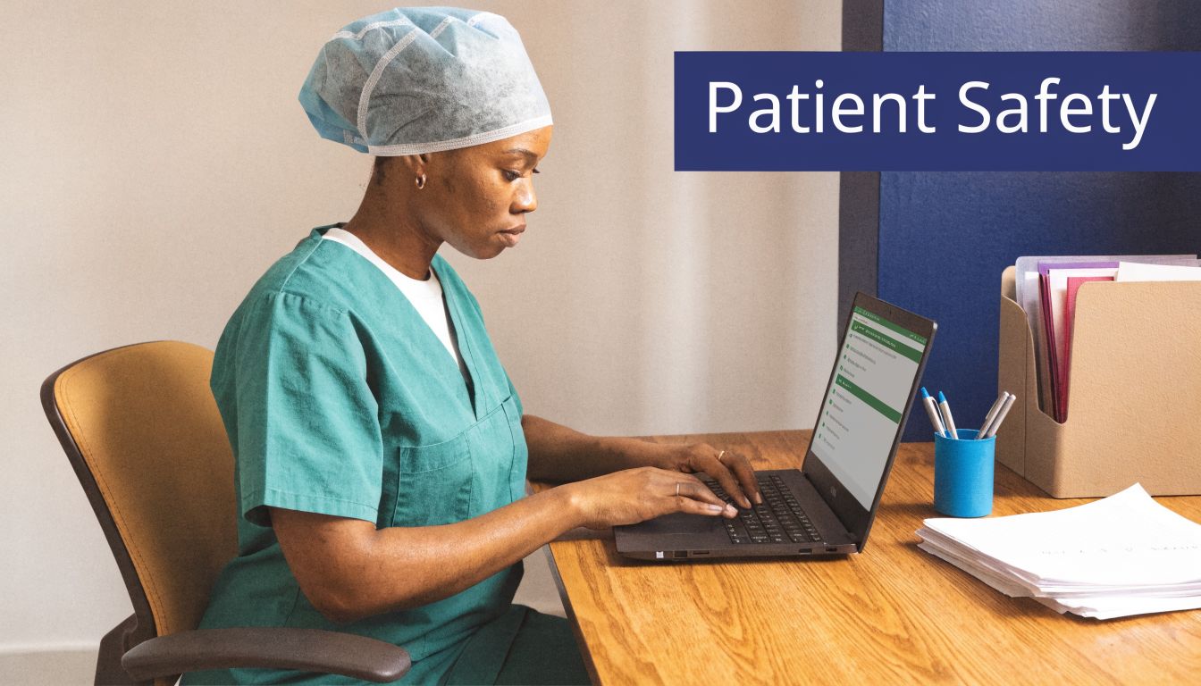 A healthcare professional wearing surgical scrubs and a scrub cap working on a laptop at a desk.