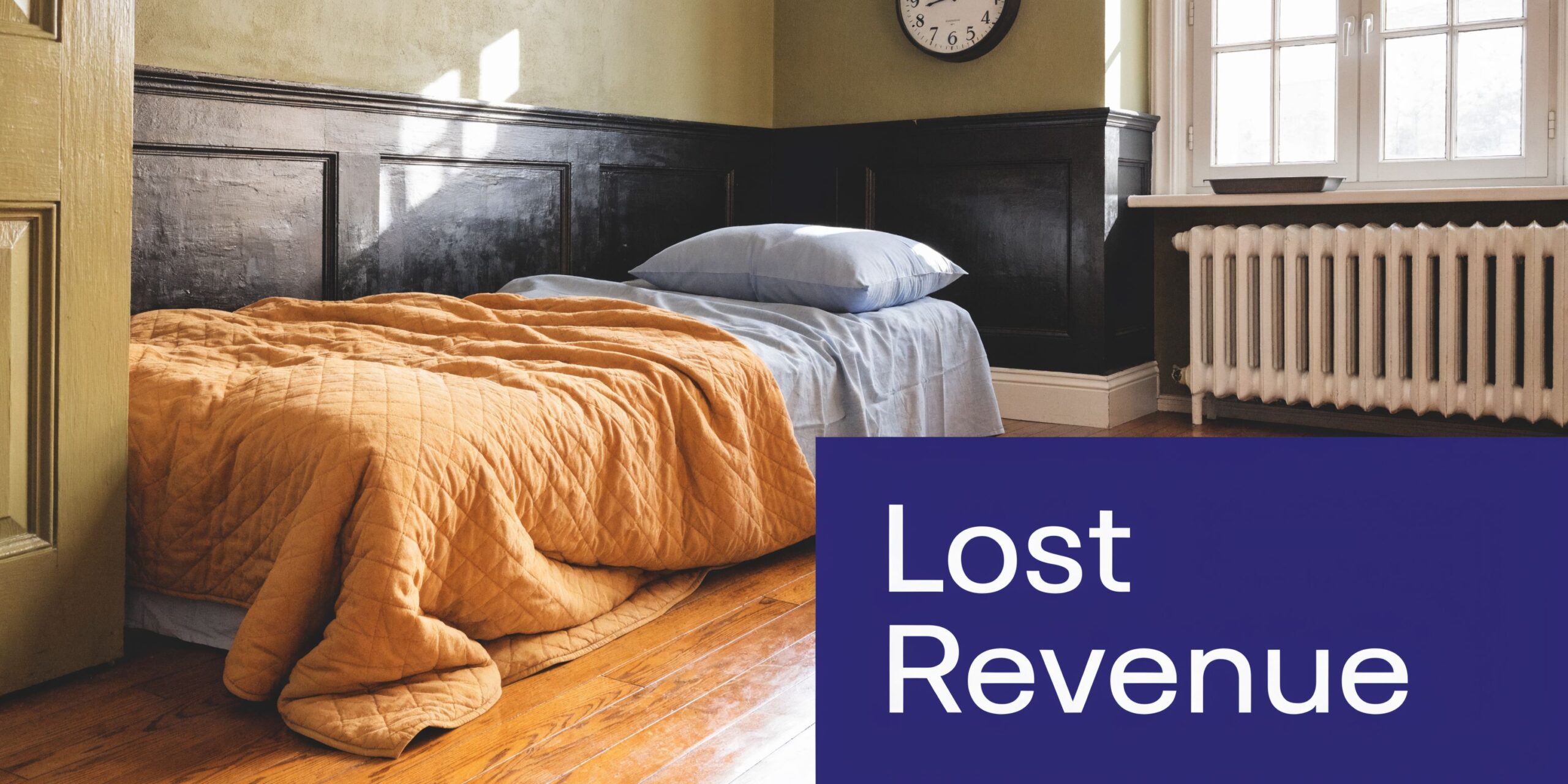 A neatly made single bed with an orange quilt in a room with black wood paneled walls.