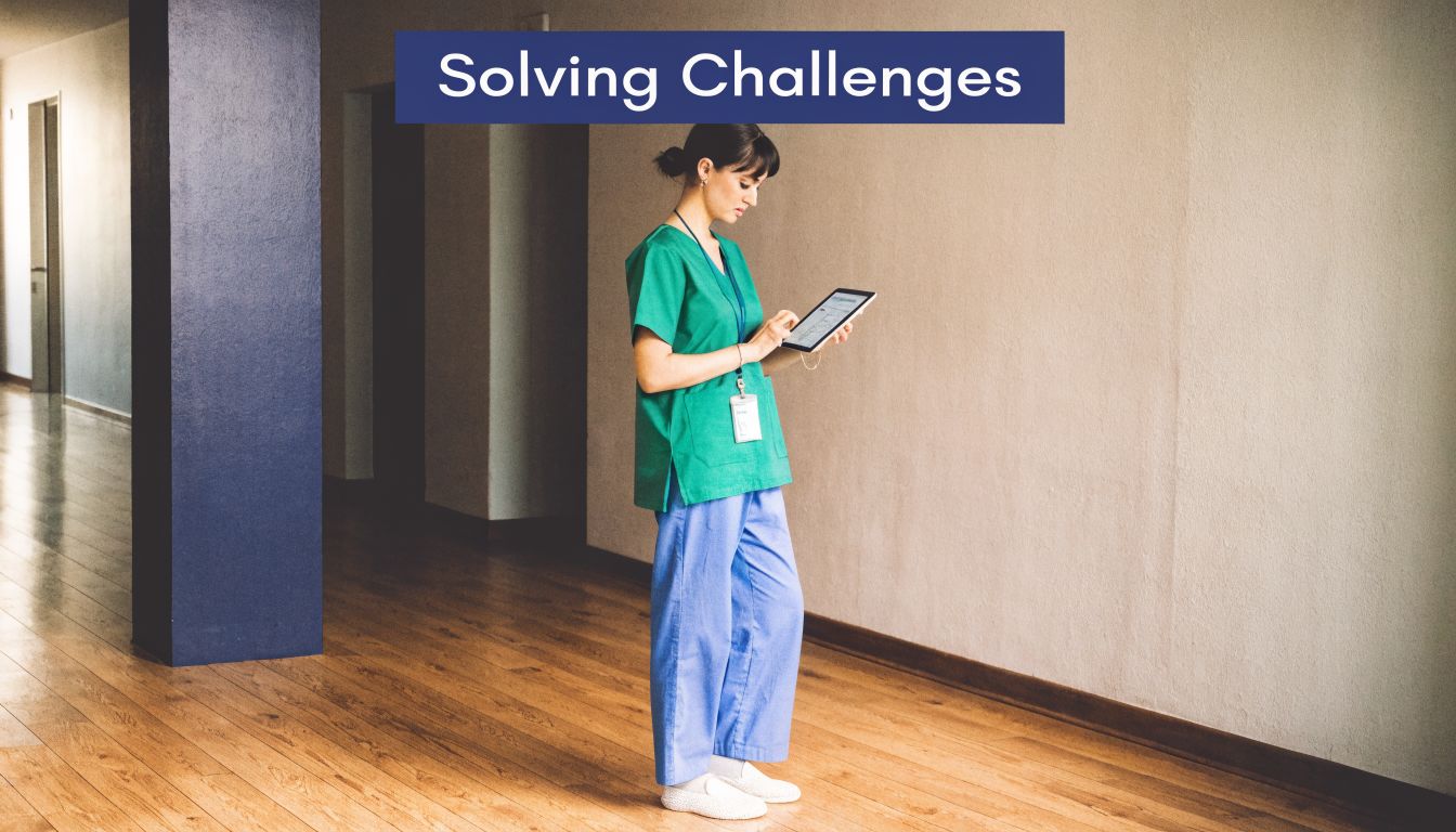 A female nurse in green scrubs reviews clinical documentation on a digital tablet in a hospital hallway.