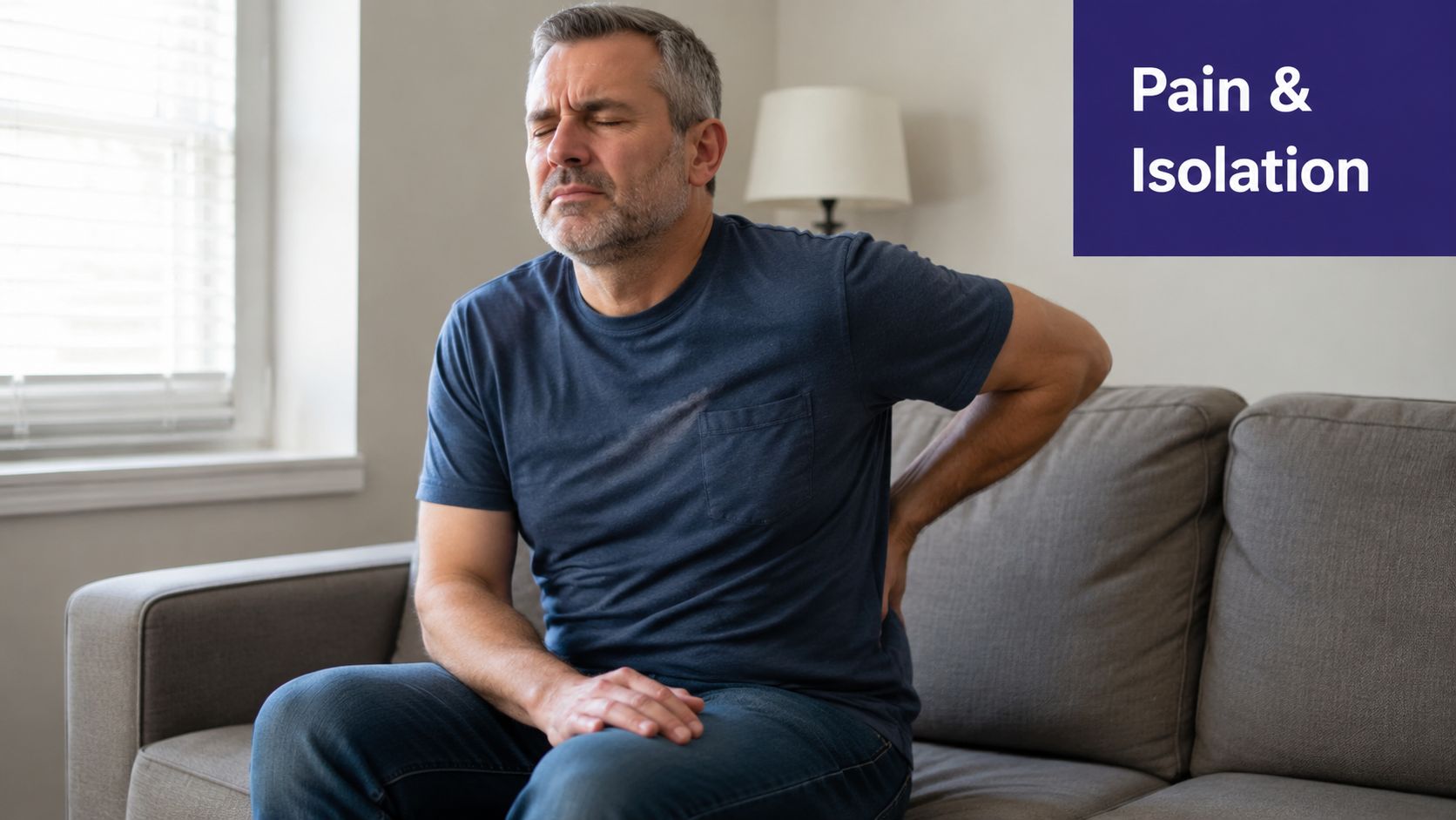 A middle-aged man sitting on a sofa with his eyes closed, showing clear signs of back pain.