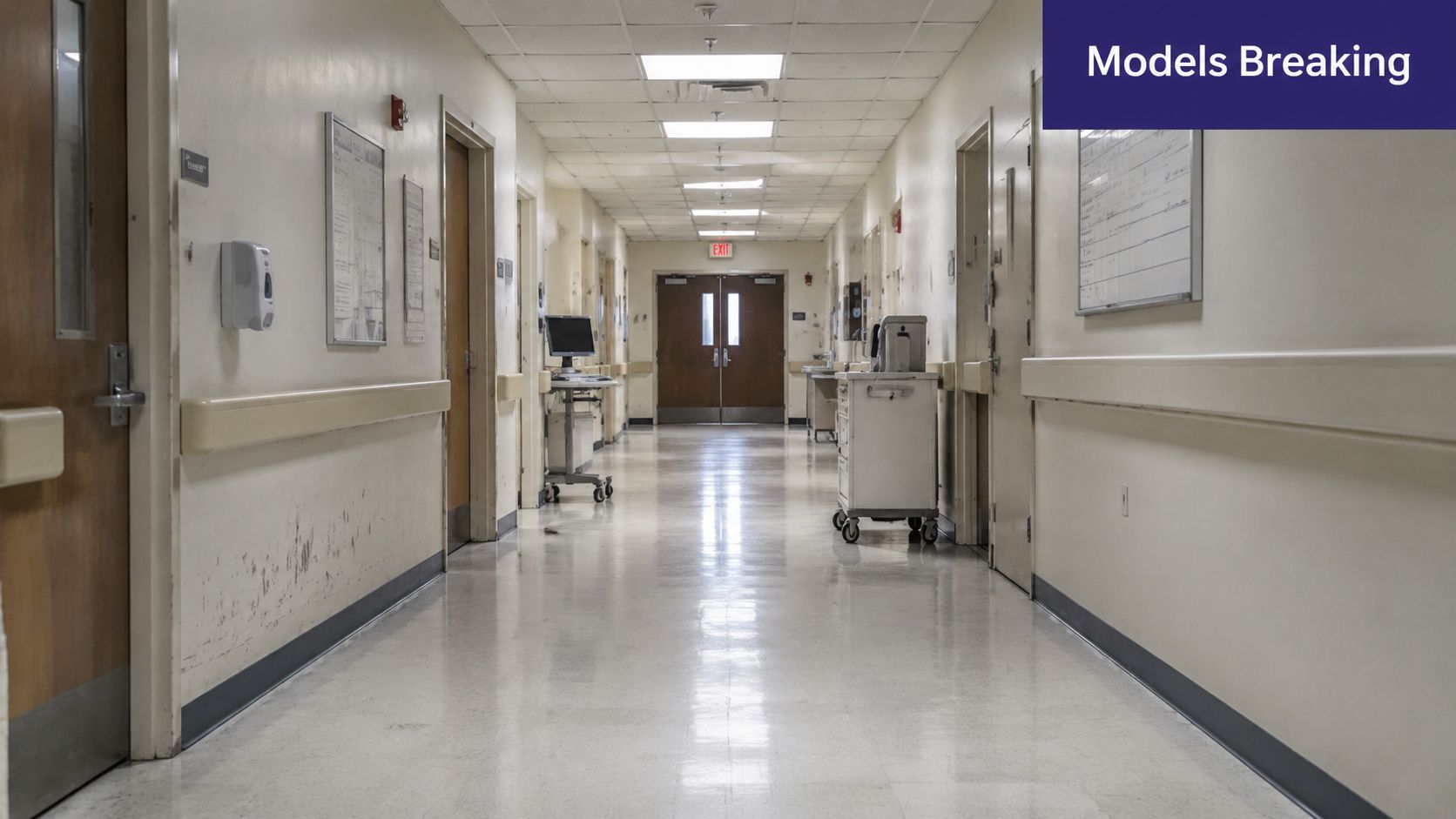 A long, quiet hospital hallway featuring closed doors, medical equipment, and a red exit sign.