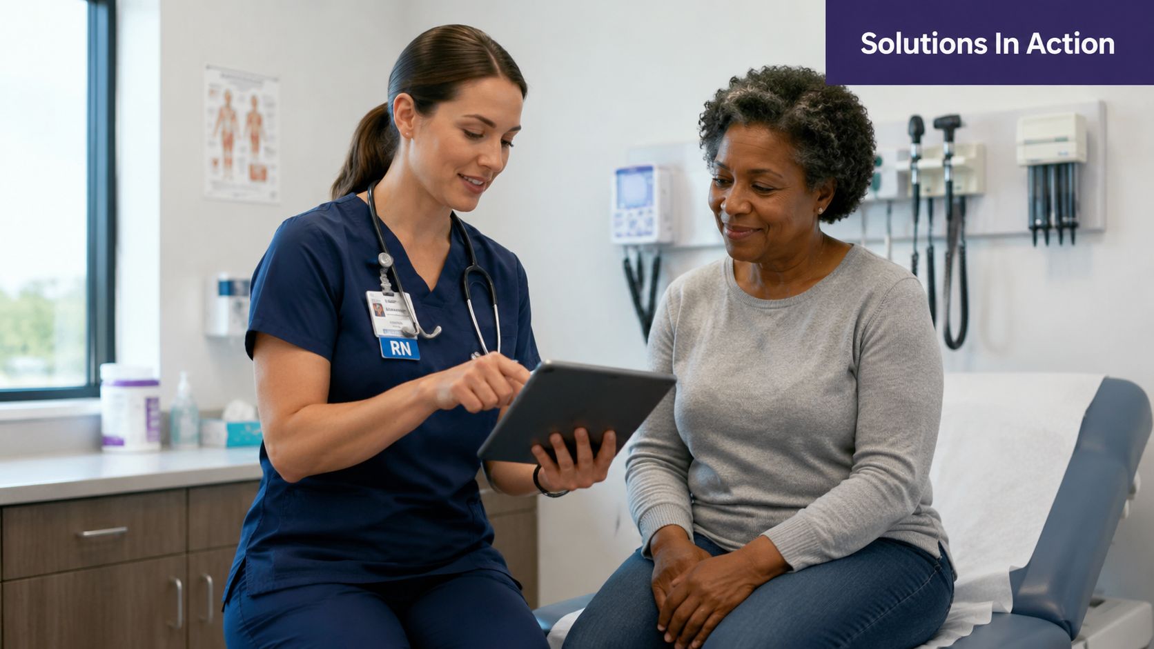A registered nurse explains healthcare information to a senior patient while using a tablet during an appointment.