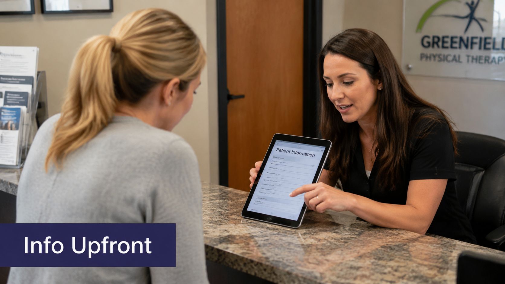A receptionist at Greenfield Physical Therapy assists a patient by explaining intake forms on a tablet.